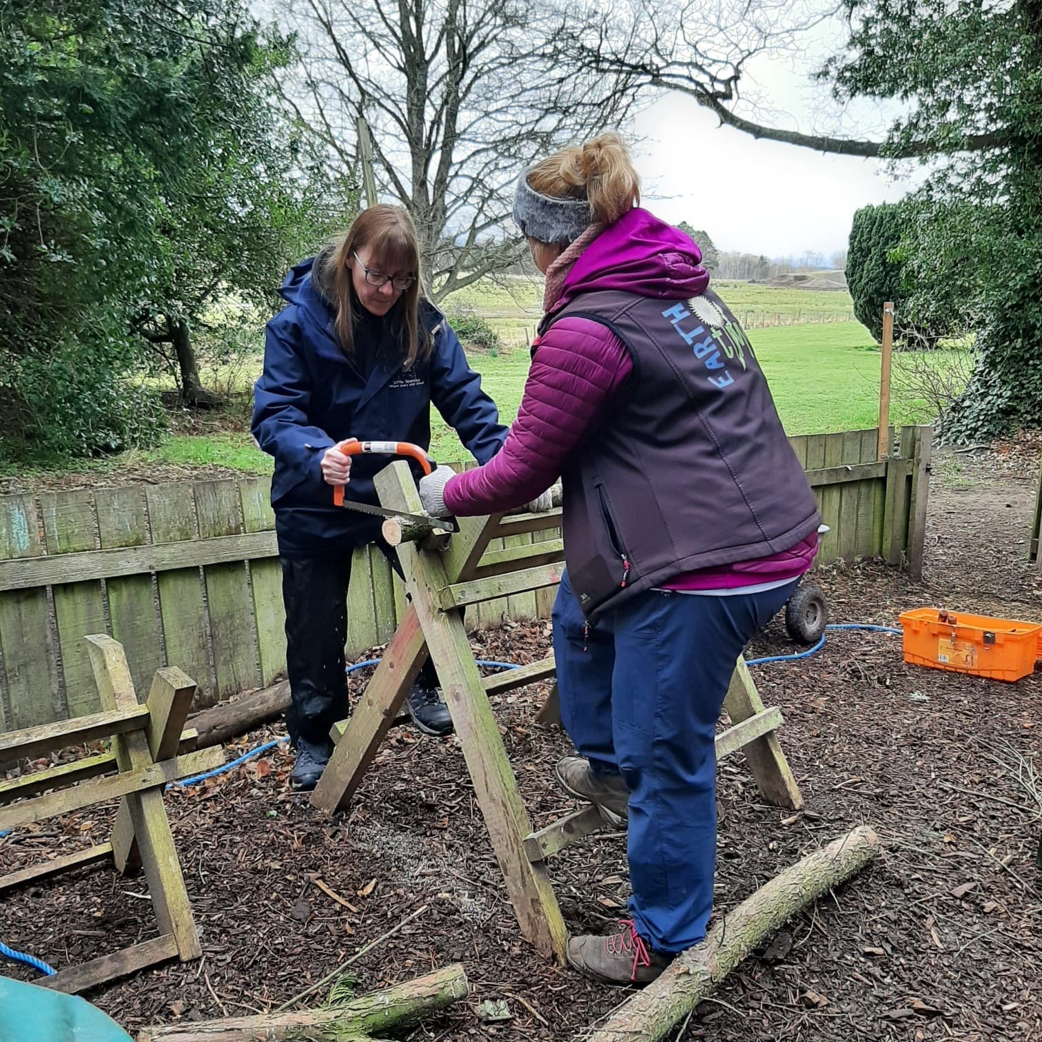 Earthtime practitioner teaching FOLA student to use a saw